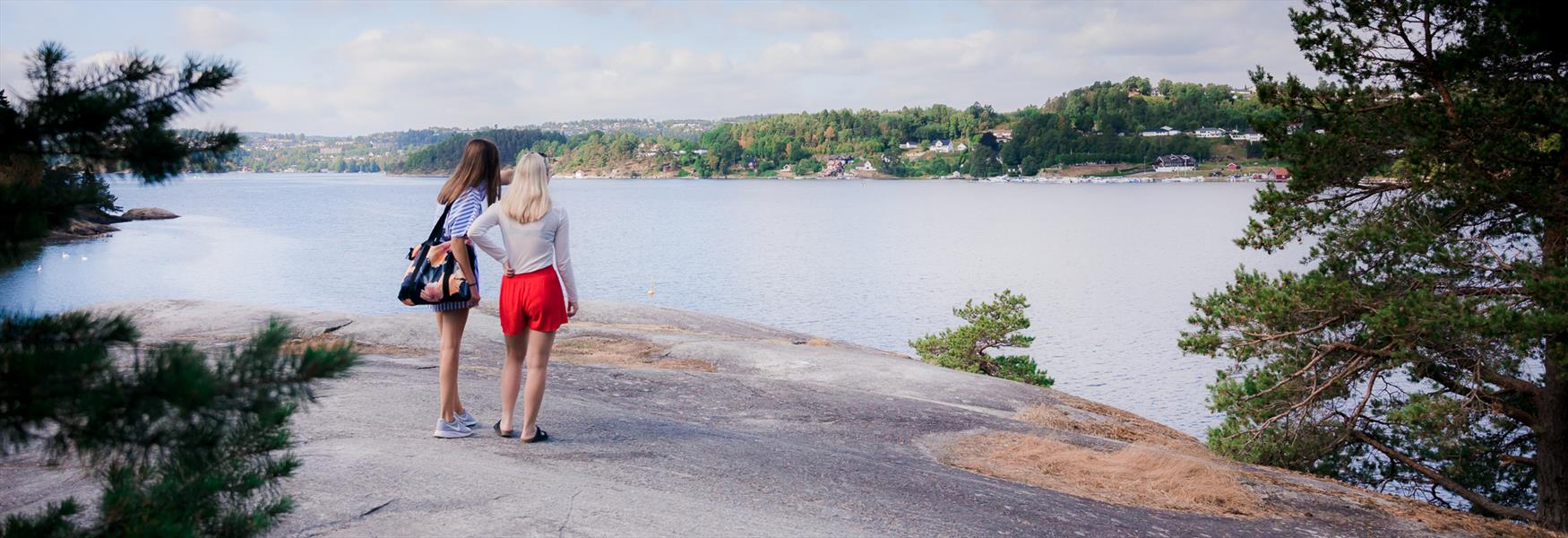 2 jenter står på en topp og ser over vannet
