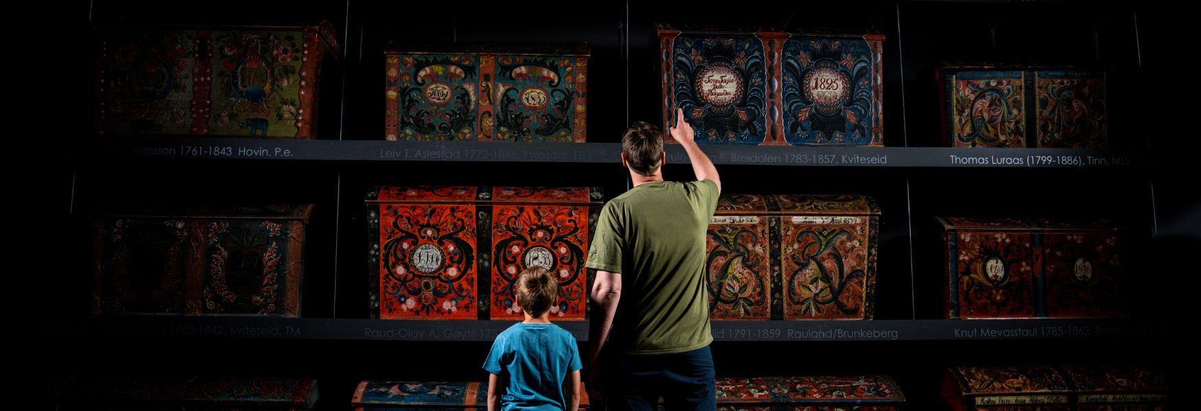 Far og son ser på rosemåla kister, Vest-Telemark museum Eidsborg.