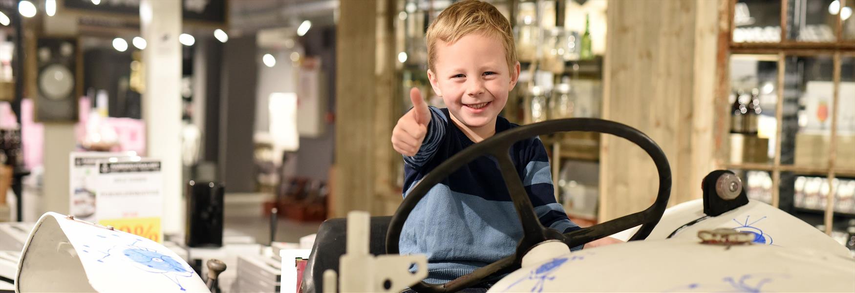 gutt sitter på traktoren Stråtass på porselensmuseet i Porsgrunn