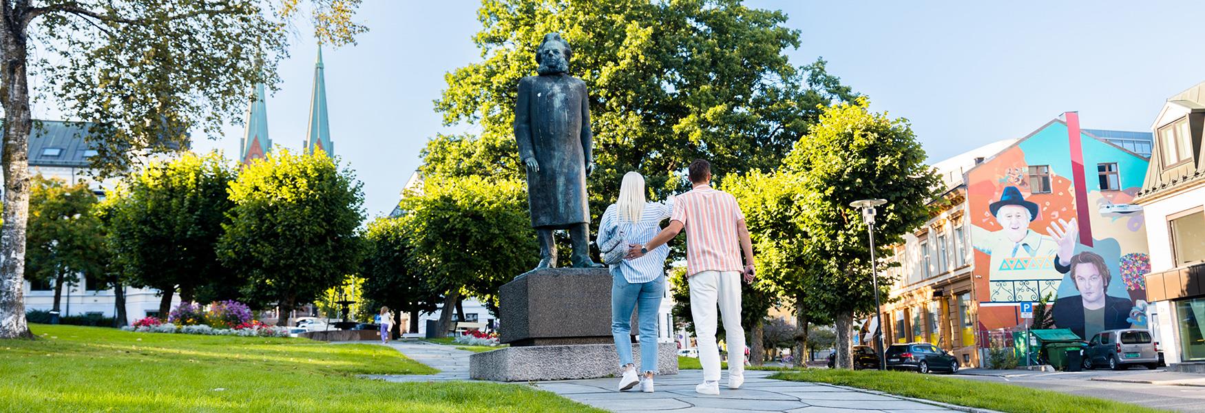 par står foran Henrik Ibsen statuen i Skien