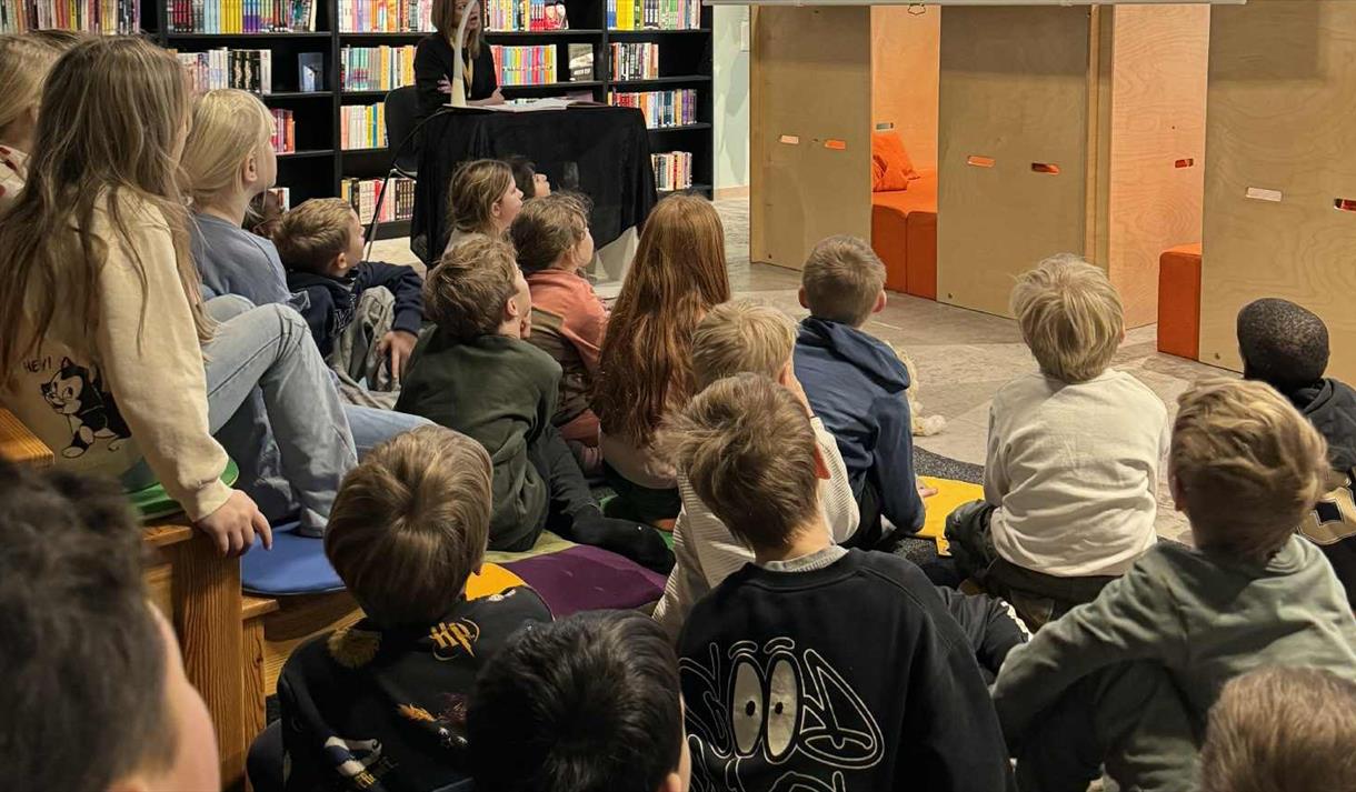 Viser et ungt publikum som deltar på en litteraturformidling på Skien bibliotek.