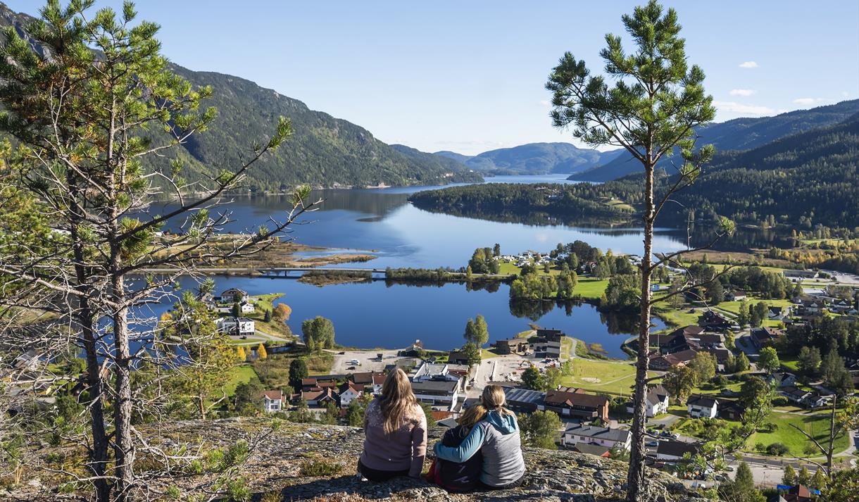 To damer og et barn sitter på Bringsåsnuten med Seljordsvatnet som utsikt.