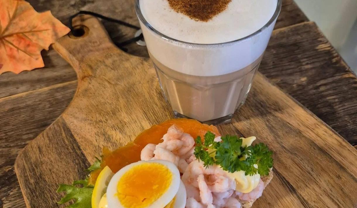kaffe med hvitt skum og brunt hjerte, smørbrød med reker og egg