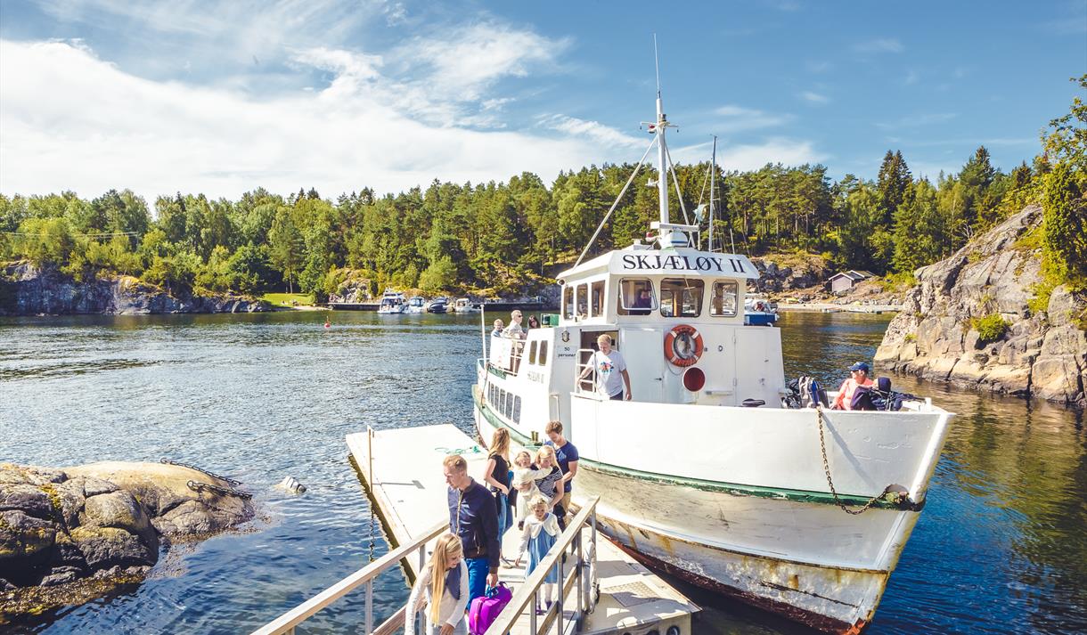 hvit ferge med passasjerer på brygge