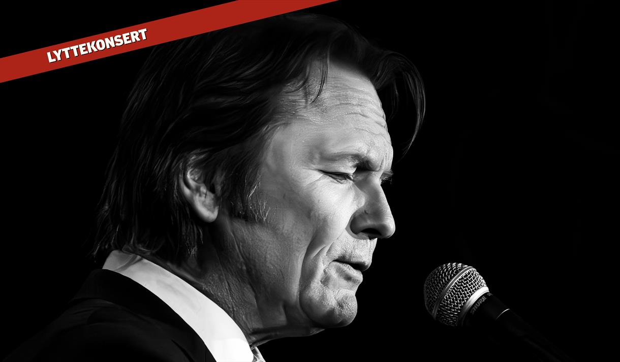 mann som synger, sort dress med hvit skjorte, rød strek med hvit tekst hvor det står lyttekonsert