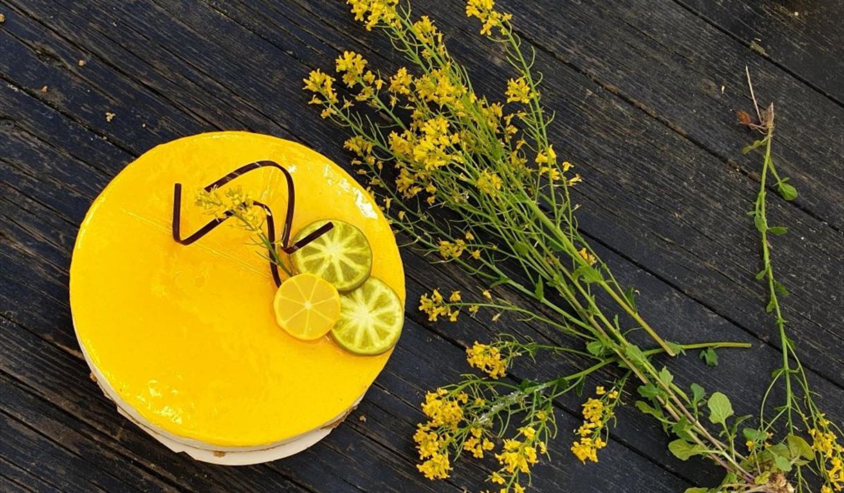 Kake med gult åelelokk, gule blomster på et brunt trebord