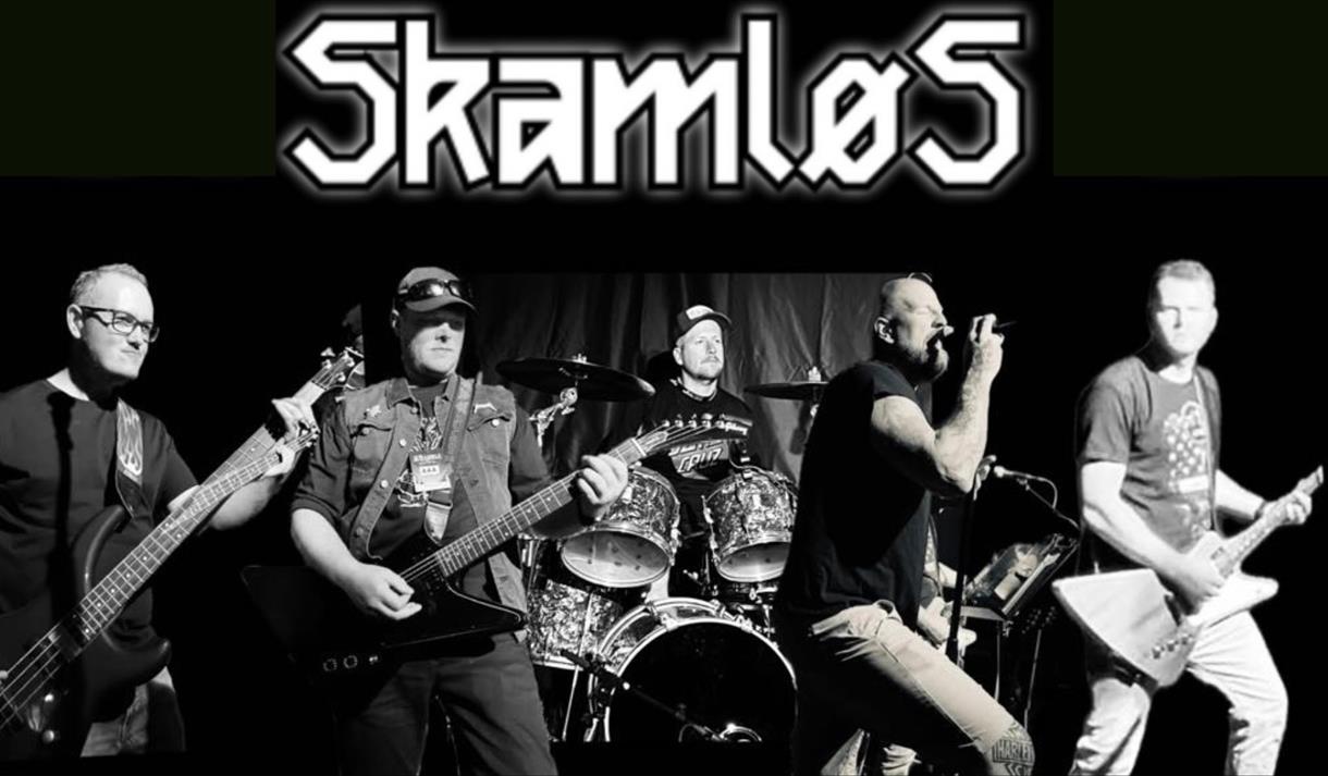 svart hvitt bilde av 5 menn på en scene, en på trommer og 3 som spiller gitar, en vokalist