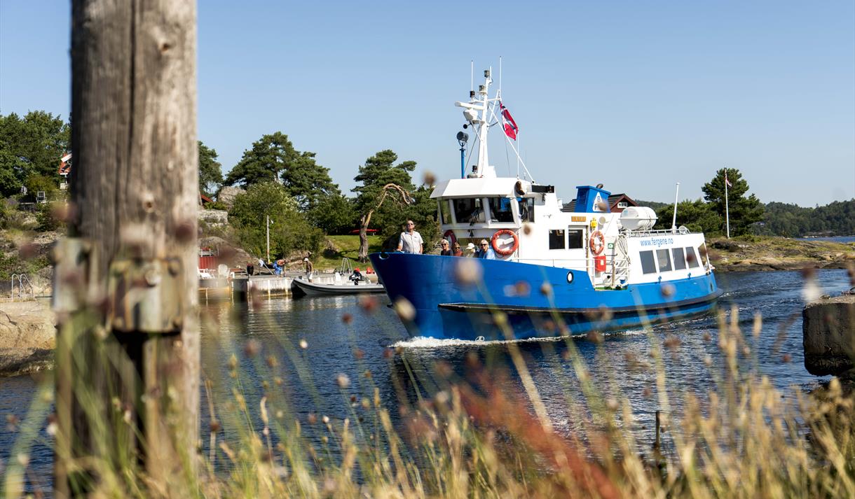 hvit og blå båt, med folk ombord