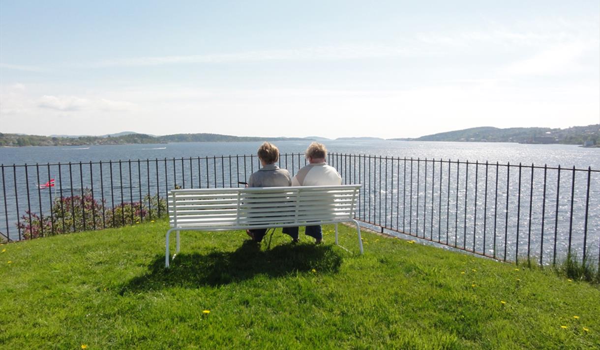 2 damer sitter på en benk på batteriet på øya i Brevik