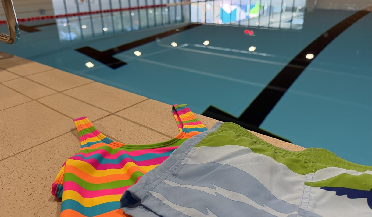 badebasseng, svømmehall med badedrakt og badebukse på kanten
