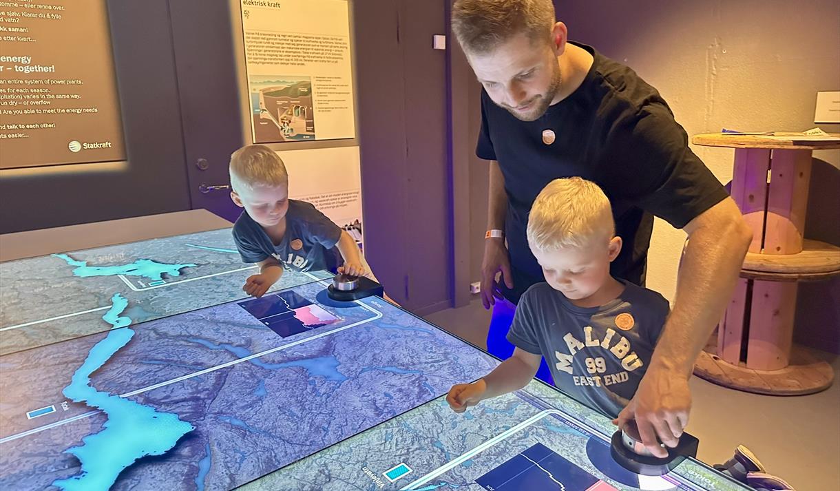 Familie ved ein av modellane i Statkraft-utstillinga på Vest-Telemark museum.