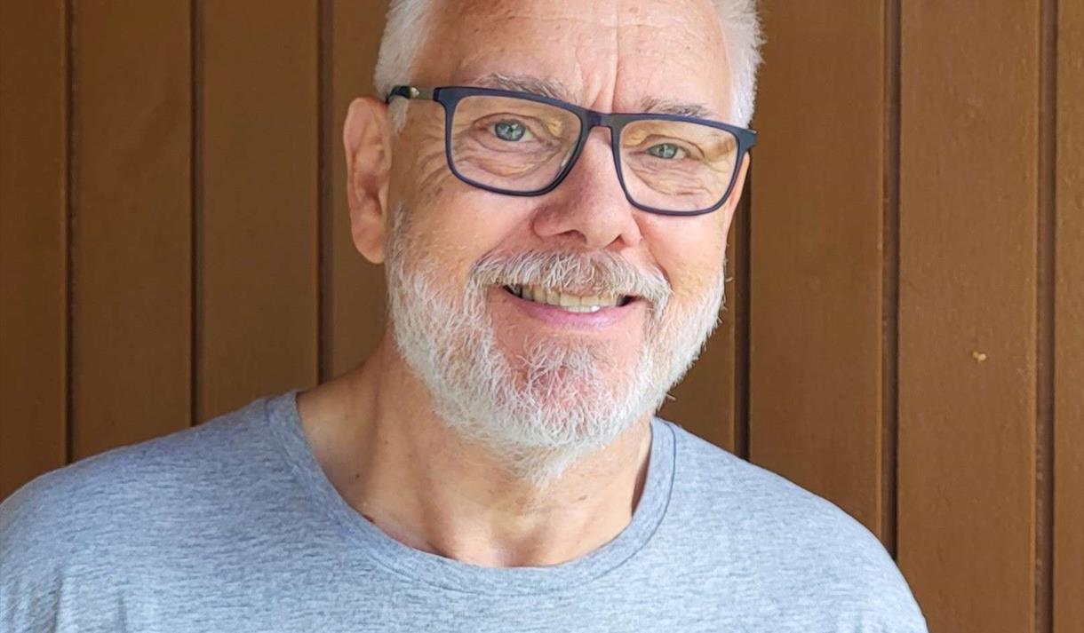 mann med briller, grått kort hår og grå genser