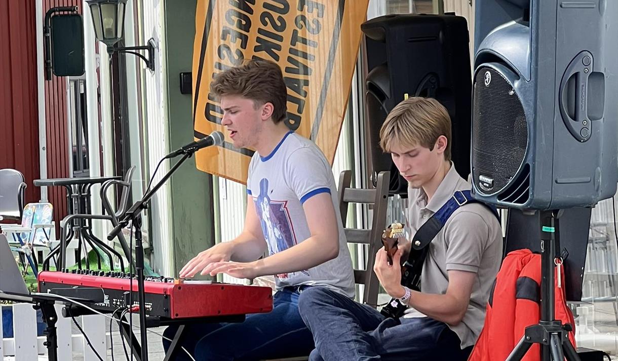 to gutter som spiller, en på rødt keyboard og en på gitar