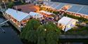 Dronefoto av Sommerfest på Becks Brasserie & Bar Osebro med utescene, restaurant og gjester langs elva i Porsgrunn.